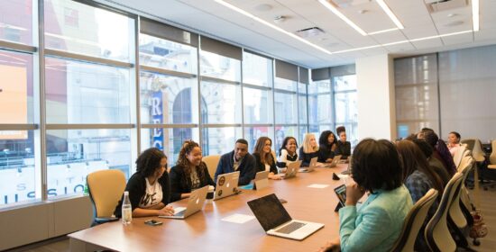 group of people sitting beside rectangular wooden table with laptops